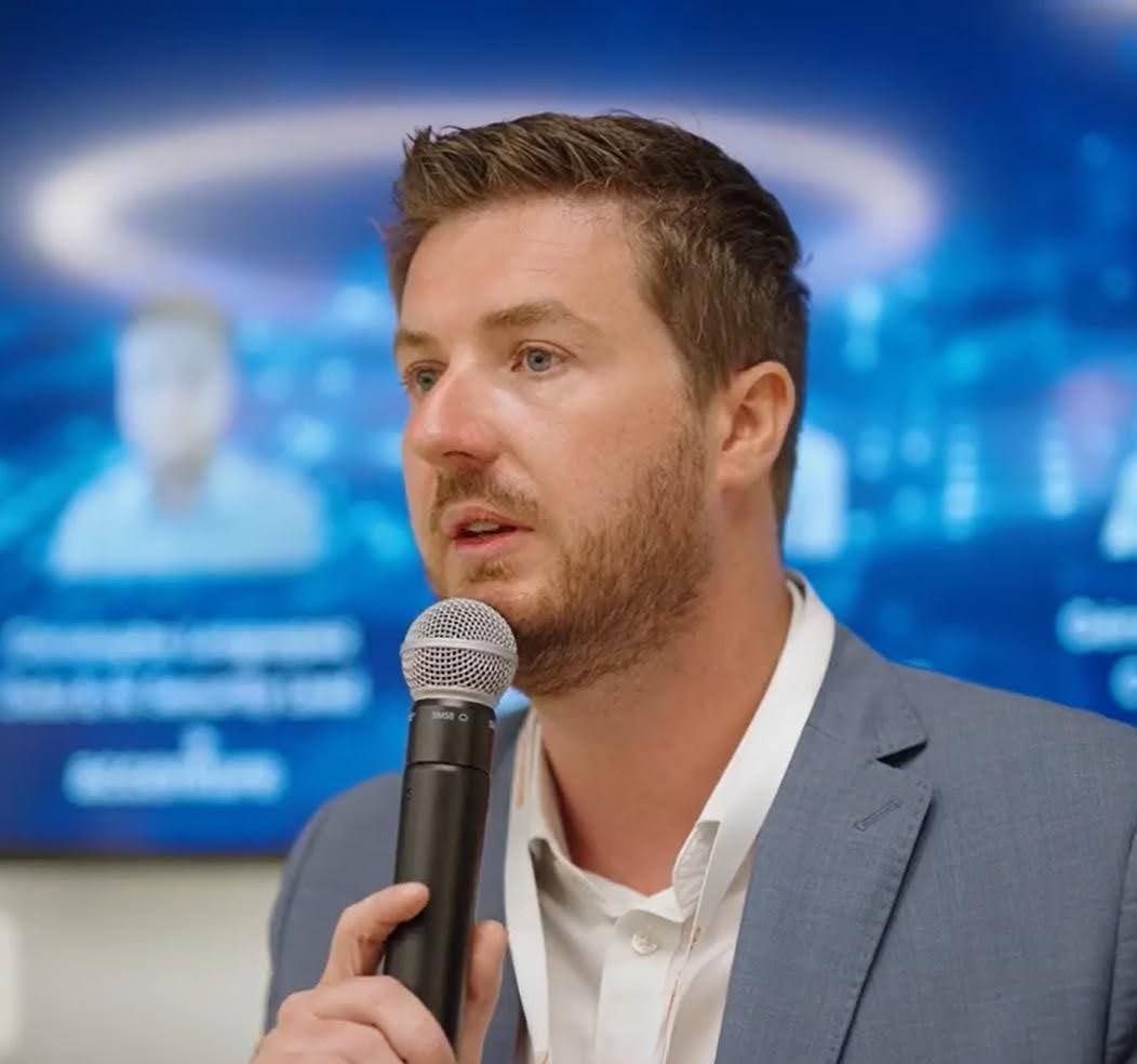 Christophe Longuepez speaking on stage, holding a microphone